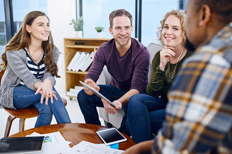 Quatre jeunes adultes en train de discuter de change mangement dans un espace de travail